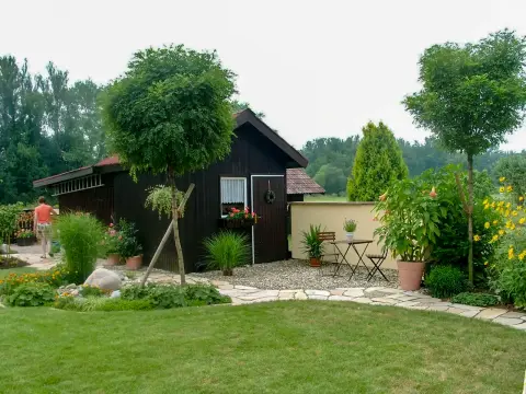 Ergebnis: dasselbe Gartenhaus in einem gegliederten Garten mit Beeten, Natursteinen und Sitzplatz
